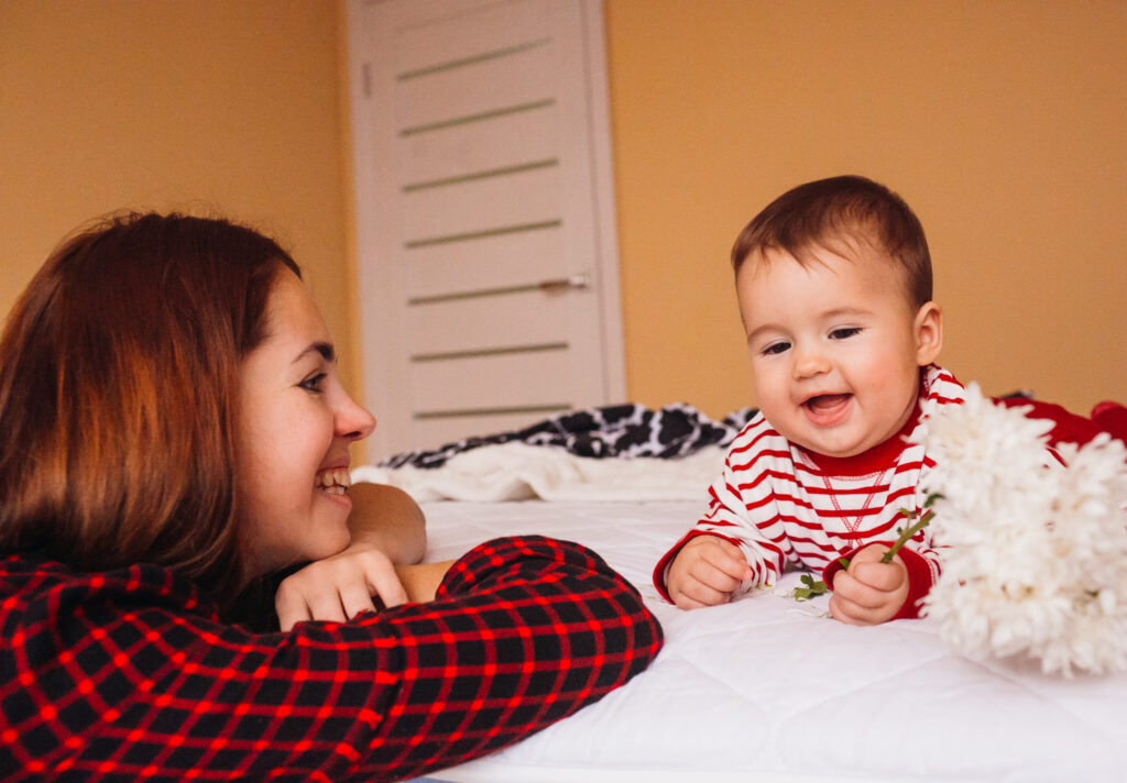 Mom With Long Red Hair Plays With Little Boy On Bed